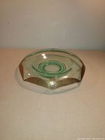 Green octagonal glass console bowl with a gold decorative band around the rim, featuring floral and geometric pattern details.