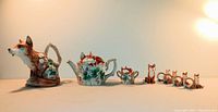 Wide shot showing the full collection of 1990 Reynard the Fox ceramic set including pitcher, teapot, creamer, four sugars, napkin holders, and Sir Algernon pitcher.