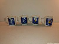 Four Morton Salt ceramic mugs with different Morton Salt girl illustrations against blue backgrounds, representing the years 1914, 1921, 1956, and 1968.