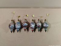 Front view of six glass Pinegrove Cardinals ornaments in blue, red, and green colors with gold hanging loops and mini cardinal pairs on top.