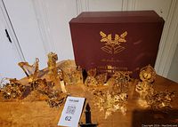 Photo showing the 11 gold coloured Christmas ornaments displayed on a table along with their original labeled box