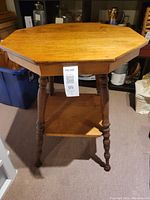 Front view of the sturdy antique wooden side table with octagonal top and turned legs.