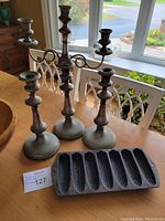 One photo showing the candleabra, two candlesticks, and cornbread pan together on a table by a window.