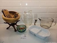 Full lot including wood carved bowl with salad utensils and stand, crystal champagne flute, glass pitcher, blue art glass bowl, white divided measuring cup.