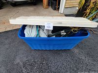 Blue Rubbermaid bin with beige lid, bin filled with various gardening and outdoor items