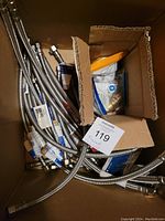 Photo taken from above showing multiple braided stainless steel faucet connectors inside a cardboard box.
