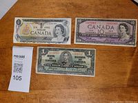 Front side of three Canadian banknotes: two one dollar notes and one ten dollar note, each with portraits and denomination visible.