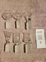 Top-down view of six heavy shot glasses showing clear upper glass and frosted bases each with unique etched pattern