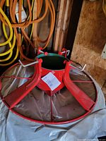 Full view of red metal Christmas tree stand showing sturdy base with four legs and water pan area