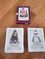Photo of three books: 'Addy An American Girl' in original box, 'Samantha's Surprise A Christmas Story' and 'Kirsten's Surprise A Christmas Story' on wooden floor.