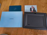 Aura digital picture frame box with manuals and frame in the packaging