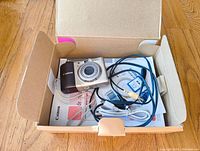 Canon PowerShot A1000 IS camera, cables, manuals inside open box