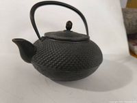 Side angle view showing spout, hobnail texture, handle, and lid