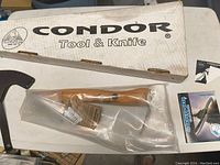 Overall view of the Condor Tools hatchet in clear plastic packaging, original box and pamphlet visible