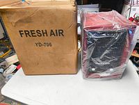 Photo showing the Fresh Air purifier next to its original cardboard box packaging labeled Fresh Air YD-706.