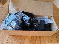 Opened cardboard box showing the headlamp securely packed with bubble wrap and cable inside.
