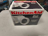 Original boxed KitchenAid slicer & shredder attachment for stand mixer, box front view showing brand and product name.