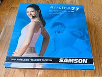 Front view of the Samson Airline 77 box showing a woman wearing the wireless headset system.