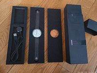 Watch and charging cable arranged in foam inserts alongside outer box