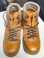 Pair of brown leather Simms boots showing front top down view with laces tied and padded beige collar.