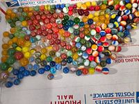 Top view of assorted vintage marbles with swirled, solid, and speckled patterns in various colors including red, blue, yellow and green.