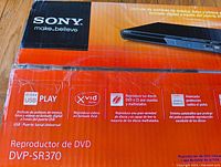 Sony DVP-SR370 DVD player box showing product features including USB play, Xvid support, advanced dust protection, and playback of scratched discs.