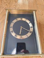 Front view showing the glass front and gold tone Roman numeral dial of the clock with Tiffany & Co. branding.