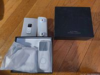 Wi-Fi doorbell camera, mounting bracket, charging base, and original black box for scale and identification.