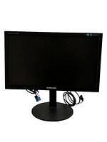 Front view of the black Samsung monitor with VGA and power cables attached, showing the screen and base stand.