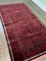 Full view of the thick Afghani handmade rug with intricate geometric and diamond-shaped patterns in red, black, and cream.