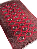 Full view of the red Afghan Bokhara rug showing diamond-shaped motifs and intricate border detail.