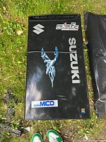 Top view of the closed Suzuki branded refrigerator on grass showing logo and decals