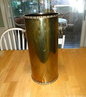 Front view of the cylindrical brass umbrella/cane holder showing its polished surface and top rim detailing.