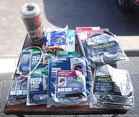 Full overhead view of weather stripping, foam tape, crack stuffer kits, foam rope, and sealant packets laid on a wooden surface in daylight.