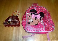 Front view of Minnie Mouse backpack and matching Minnie Mouse purse placed on a wooden floor.