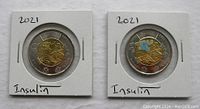 Obverse and reverse of two 2021 Canadian Toonie coins, one plain and one coloured, each in individual 2x2 holders.