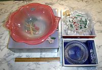 Photo showing two Mikasa dishes and a boxed wine set arranged on a marble surface with a ruler for size reference