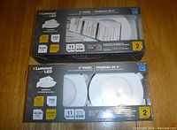 Front view of two unopened packages of Luminus LED 4-inch Panel Pot Lights showing 2 lights per package, 11 watts, 2700K color temperature, 700 lumens, dimmable, 65W equivalent.