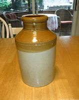 Front view of the crock showing two-tone brown and beige glaze with decorative band near top.