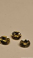 Three oval natural yellow sapphires laid flat on a surface showing color and cut.