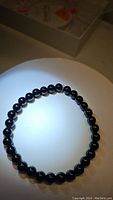 Front view of natural black onyx beaded stretch bracelet on white background demonstrating bead color and size.