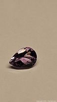 Close-up of the pear-shaped purple amethyst gemstone displaying facets and clarity.