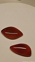 Pair of natural carnelian stones on a plain background showing their color, shape and polish.