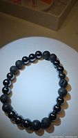 Top view of the bracelet showing natural porous black lavastone beads alternating with shiny, smooth hematite beads.