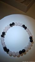 Beaded bracelet arranged in a circle showing alternating rose quartz and black onyx beads under natural lighting