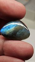 Close-up photo of the pear-shaped labradorite gemstone capturing its blue flash and natural color variations.