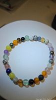 Photo of a natural mixed gemstone stretchy bracelet showing various colored round polished beads arranged in a circle.