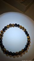 Yellow tiger eye gemstone round bead stretchy bracelet shown on white circular surface in soft lighting.
