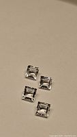 Four natural white topaz gemstones in square cuts shown on plain background.