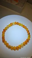 Yellow agate bead bracelet laid out flat showing round polished beads in gradient yellow and orange hues.